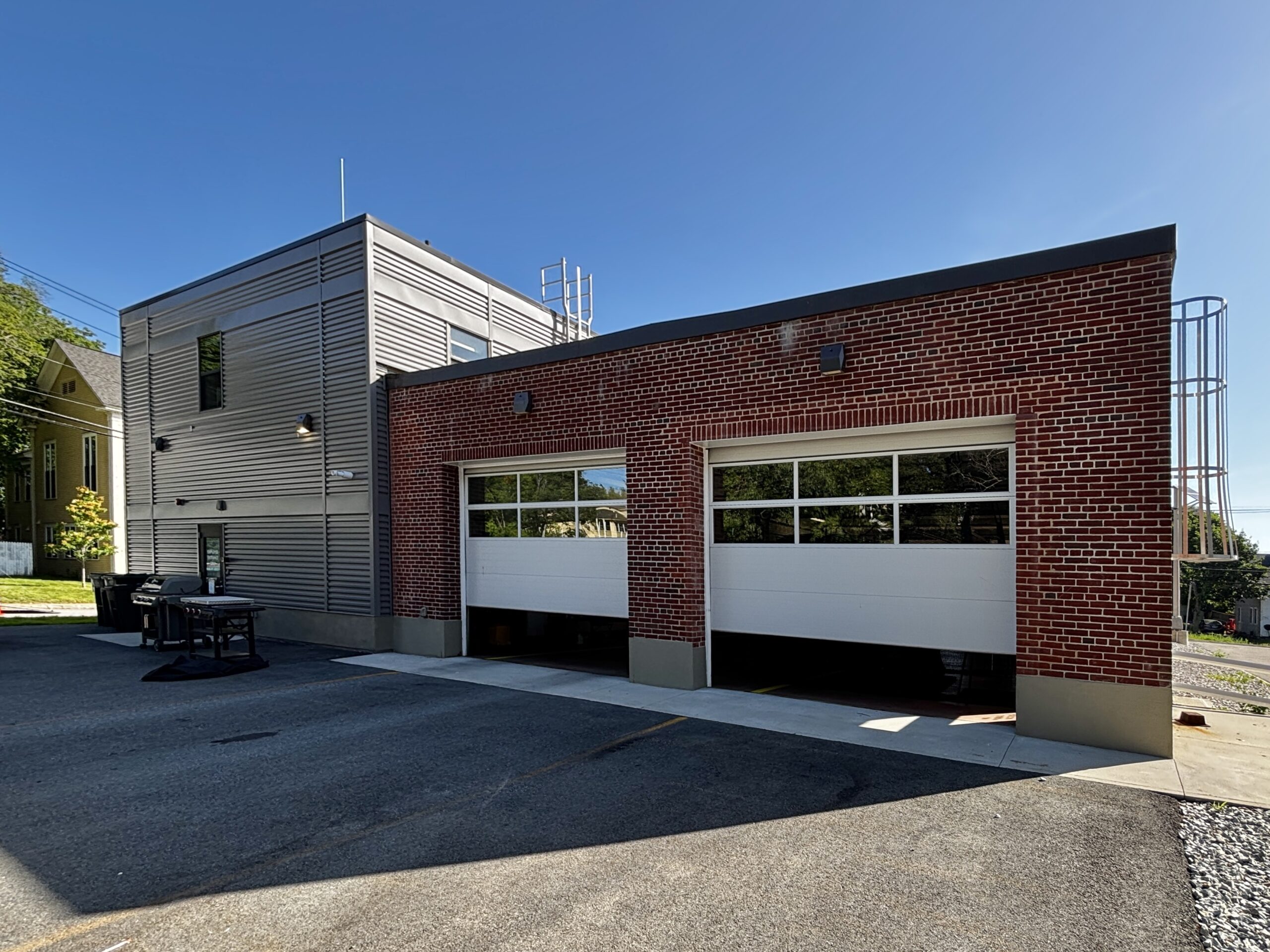 Back of fire station with two apparatus bay doors open.