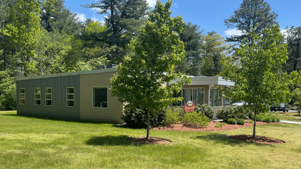 Triumph modular building surrounded by greenery, showcasing modern modular construction with a well-maintained garden and trees.
