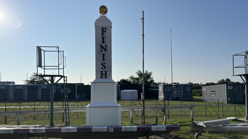 Suffolk Downs, Boston MA track finish line pole with Triumph trailer in the background